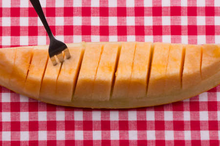 Freshly cut melon on checkered tablecloth.の写真素材