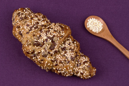 Close up of a sesame seed croissant, viewed from above on a purple background.の写真素材