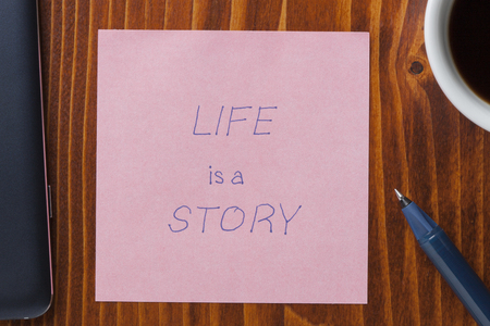 life is a story handwritten text on a note with pen.