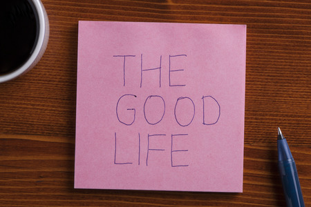 The good life handwritten on a note on wooden background with pen.の写真素材