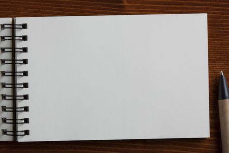 Recycled paper notebook and recycled paper pen on wooden table.
