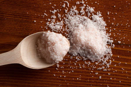 Himalayan salt in wooden spoon on wooden table.