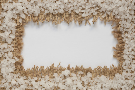 Frame of sea salt on piece of burlap with white background inside.の写真素材