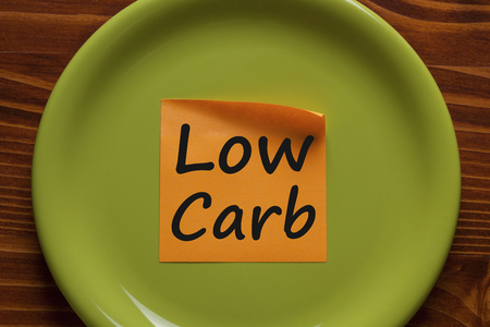 Low carb written in orange sticky note on the green plate.Business concept.Top view.の写真素材