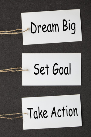 Dream Big Set Goal Take Action text on white blank paper labels set on the black background.の写真素材