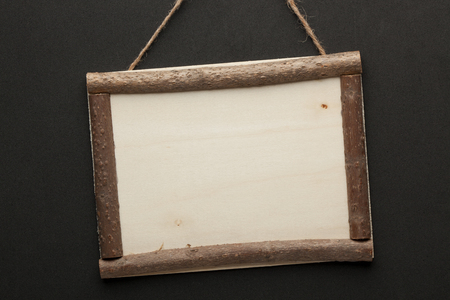 Blank wooden sign hanging on a rope on black background. Empty place for your textの写真素材