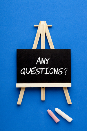 Text ANY QUESTIONS on blackboard on tripod with chalk. Business Concept.の写真素材