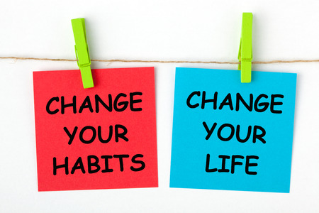 Change Your Life by Changing Your Habits text written on color notes with wooden pinch.の写真素材