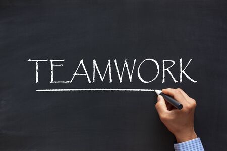 Men hand writing word Teamwork with chalk marker on blackboard. Business concept.の写真素材