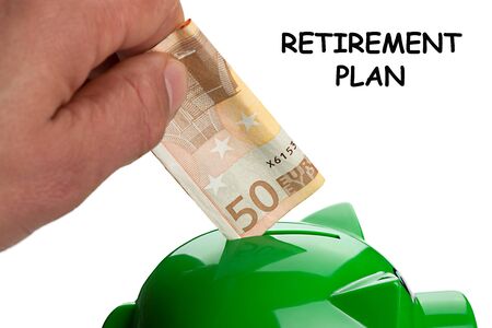 Hand putting banknote on a piggy bank and text Retirement Plan. Stop working. Pension concept.の写真素材