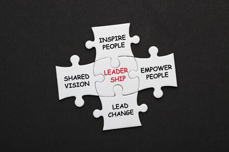 Leadership with conceptual words in pieces paper puzzle on black background. Business concept.