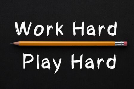 Work Hard and Play Hard text with pencil on black background. Motivational quote.