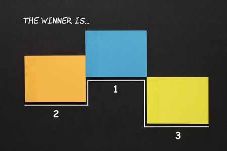 Text The Winner Is... on notes in the shape of a pedestal for winners.