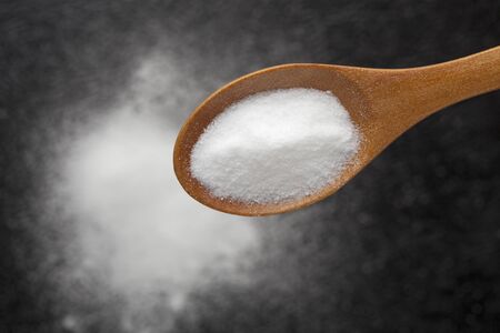 Baking soda on a wooden spoon. Sodium bicarbonate