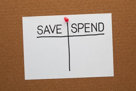 Save and spend concept on white paper sheet pinned on cork board. Empty list