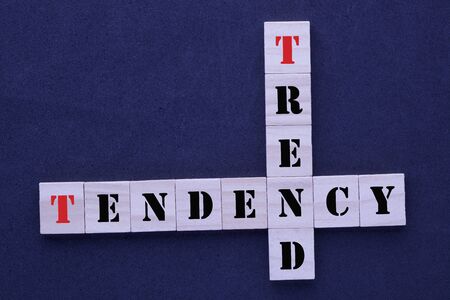 Crossword with words trend and tendency in wooden blocks on black background.の写真素材