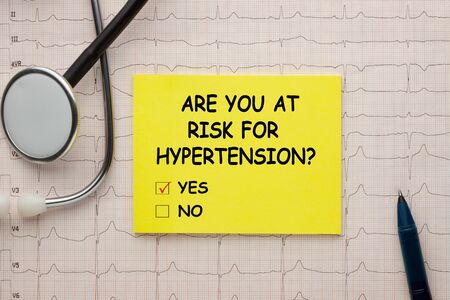 Are you at risk for hypertension question yes or no text on note with stethoscope and heartbeat rate, cardiogram and EKG concept.の写真素材