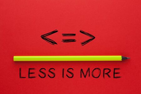 Less is more phrase and pencil on red background. Business concept.