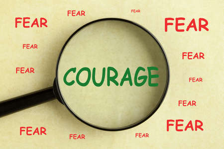 Magnifying glass over the word courage and fear concept backgroundの写真素材