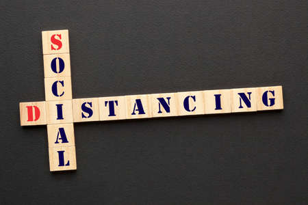 Social Distancing text on wooden crossword puzzle on a black background. Coronavirus COVID-19