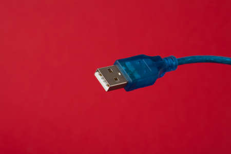 Blue USB universal serial bus data cable on red background.の写真素材