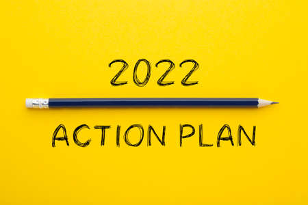 Action Plan 2022 text and pencil on yellow background. New year business vision.の写真素材