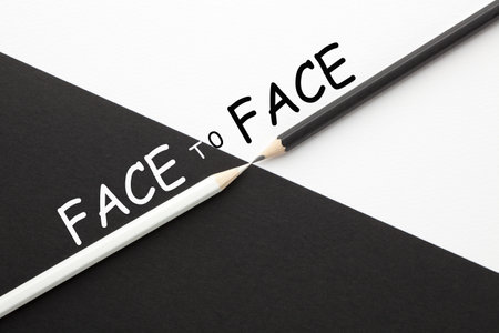 Face to Face text with black and white pencils facing each other.の写真素材