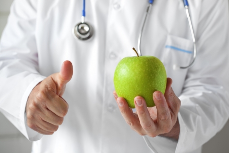 Doctor with green apple in hand in the consulting room の写真素材