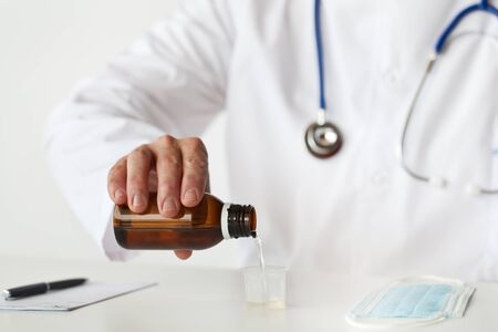 Doctor is filling a cup with cough syrup  