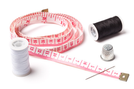 Sewing measuring tape, threads, needle and thimble on white.