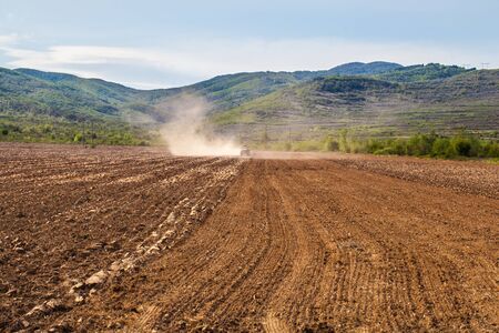 A tractor is cultivating the soil before sowing in the early spring. The machine perform this...
