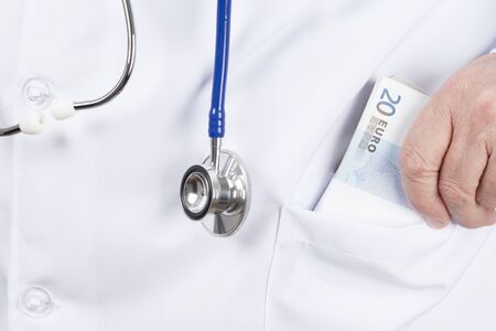 Doctor in a white tunic putting a wad of money in the pocket.