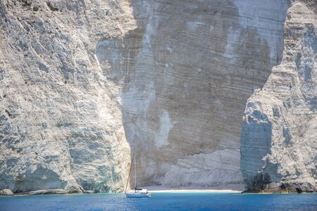 One lonely boat anchored in a deserted sea bay with a small empty beach.