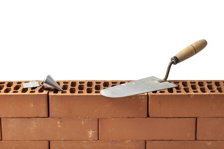 Construction tools trowel and plumb bob left on a new brickwork isolated on white.の写真素材