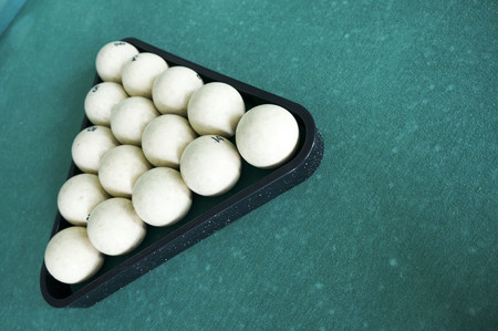 Russian billiards - large white balls with an orange cue and a wooden cue on a large table with green clothの写真素材