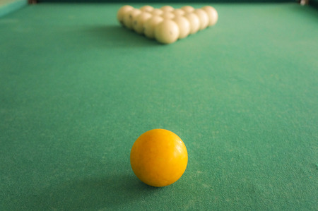 Russian billiards white balls, yellow cue ball, wooden cue on a large table with green clothの写真素材