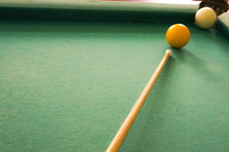 Russian billiards white balls, yellow cue ball, wooden cue on a large table with green cloth