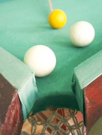 Russian billiards white balls, yellow cue ball, wooden cue on a large table with green cloth