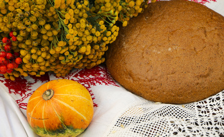 Autumn still life - loaf, pumpkin, mountain ash, tansy, wheat ears, salt,
on a white tablecloth with laceの写真素材
