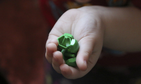 children's mosaic. the child lays a flower out of a colored plastic mosaic. a child's hand holds a bright plastic mosaic piece - collects a pattern. training, development of children's motor skills.の写真素材