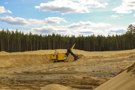 Excavators at  Sand Quarry Big  orange digger in open sand mine is waiting for new shift.