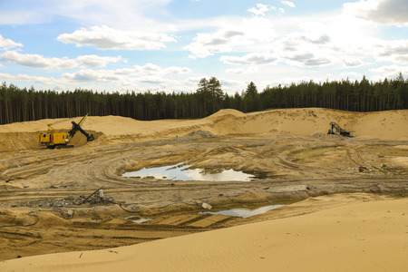Excavators at  Sand Quarry Big  orange digger in open sand mine is waiting for new shift.の写真素材
