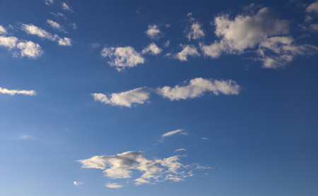 evening blue sky with white clouds. sun hides behind the clouds. rays of sun at sunset illuminate...