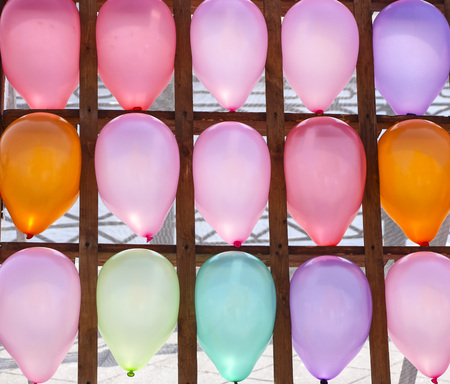 Multi-colored balloons in  cells. Inflatable multi-colored balls in  wood cells for playing darts,...