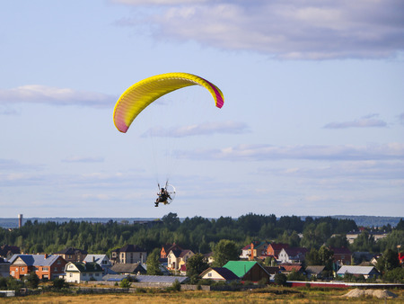 Flight of  motor paraplan.   man flies on  bright colorful motoparaplane above the village, field...