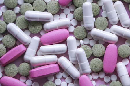 white, pink and green pills on  pink background. multi-colored drugs.の写真素材
