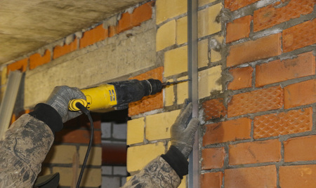 men's hands in the working gloves, drill a hole in the steel profiles, to install the frame under the insulation.の写真素材