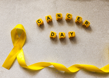 golden ribbon and words made up of children's plastic beeches. concept - a symbol of childhood cancer, pediatric oncology.の写真素材