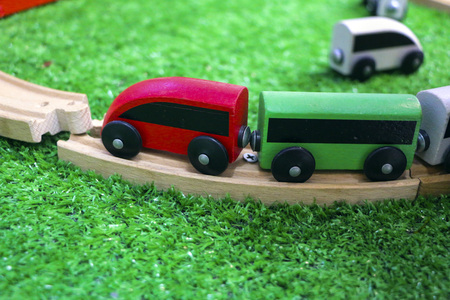 Children's wooden train with cars, railway and wooden trees on artificial plastic green grass.の写真素材