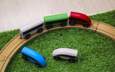Children's wooden train with cars, railway and wooden trees on artificial plastic green grass.の写真素材